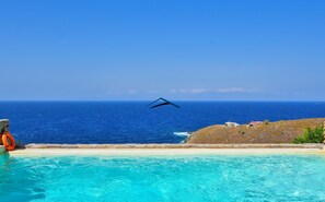 Un cielo azul despejado, una piscina y vistas al océano.