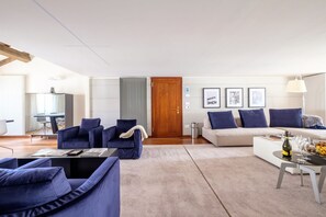 Een moderne woonkamer met een bank, fauteuils, een salontafel en een eethoek.