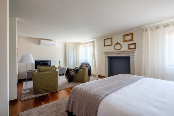 Ein Hotelzimmer mit Bett, Schreibtisch, Sessel, Kamin und Fernseher.