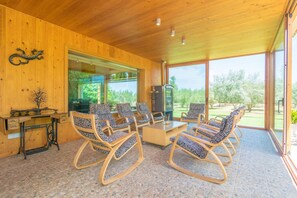 Relax in this spacious room with a high ceiling, featuring a large seating area with six comfortable chairs and a central coffee table.