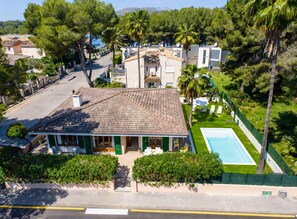 Una villa con techo de tejas, piscina y exuberante vegetación.