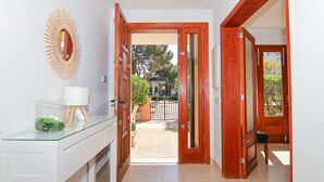 Un couloir avec une console dont le plateau est en verre, une porte en bois et une vue sur l’extérieur.