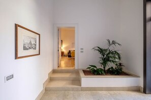 A staircase leading to a room with a framed picture on the wall, a potted plant, and a visible door to another room.