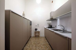Una cocina compacta con estufa a gas, lavamanos y armarios.