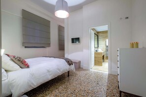 Un dormitorio con cama, mesita de noche, armario y televisor.