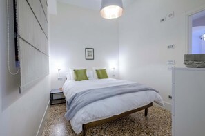 Une chambre à coucher avec un lit, des lampes de chevet, un tableau encadré au mur et une petite table de chevet.