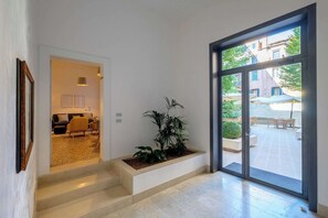 Un intérieur moderne avec un escalier menant à un espace de vie, une grande fenêtre offrant une vue sur l’extérieur et une plante en pot.