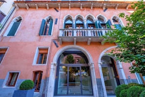 A building with arched windows, a balcony with ornate railings, and a glass entrance.