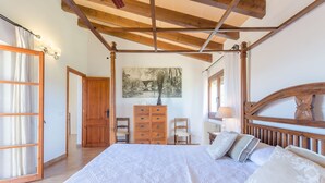 A bedroom with a large bed, wooden headboard, a dresser, and a painting on the wall. - ANGIGAL - Spectacular villa with private pool in the tranquility of the countryside. Free (Manacor)