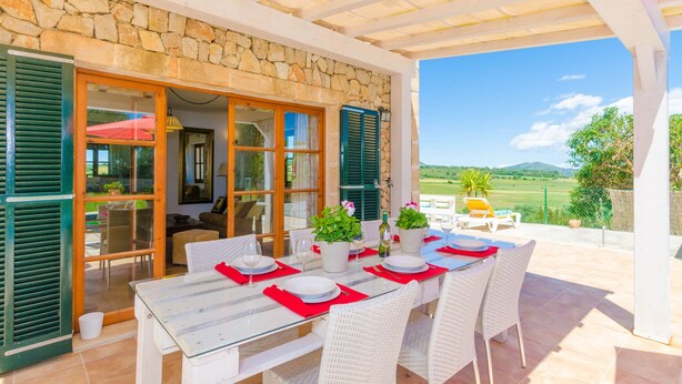 An outdoor dining area with a stone wall, wooden shutters, and a view of the countryside. - ANGIGAL - Spectacular villa with private pool in the tranquility of the countryside. Free (Manacor)