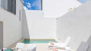 A poolside area with white lounge chairs and a table set for two, a small pool, and a white building with shutters. - NA VALENTA - Villa with private pool in Artà. Free WiFi (Artà)