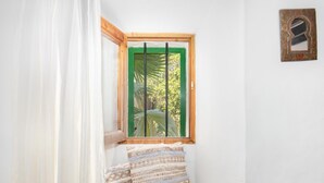 A room with a window, a small bench, and a wall-mounted light fixture.
