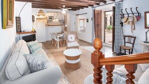 A cozy living room with a sofa, a dining table, and a kitchen area.