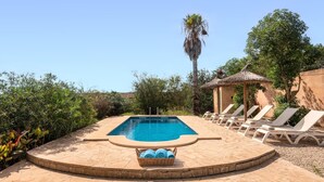 A swimming pool with lounge chairs and a thatched-roof structure.