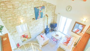 A spacious living area with a stone wall, a fireplace, a sofa, a TV, and a staircase. - Helona: Villa Estate, heated pool, stunning views, A/C (Kelia - Kassiopi)