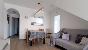 Una sala de estar acogedora con un sofá, una mesa de comedor con sillas y una zona de cocina con armarios.