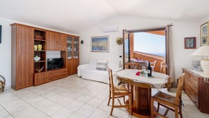 Un vaste espace de vie comprenant une table à manger, des meubles en bois, un téléviseur et un balcon avec vue.