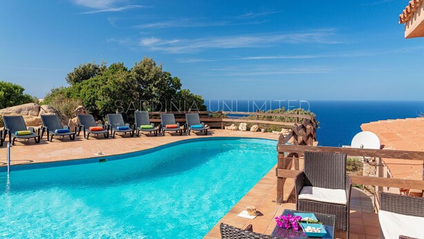 Un espace piscine avec des chaises longues et vue sur la mer.