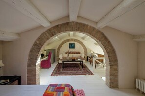 A room with a bed, a sofa, a coffee table, and a patterned rug.