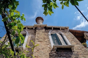 A historic building with a stone facade, a chimney, and a window with shutters.
