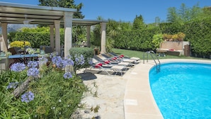 Un espace piscine avec des chaises longues et une pergola.