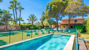Ein Swimmingpool mit Liegestühlen, umgeben von Bäumen und einem Gebäude mit einem Ziegeldach.