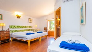 Ein Hotelzimmer mit zwei Betten, Holzboden, einem Schreibtisch mit Lampe und Blick durch ein Fenster.
