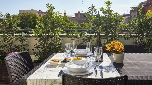 Une table dressée à l’extérieur, avec en arrière-plan des bâtiments et des arbres.
