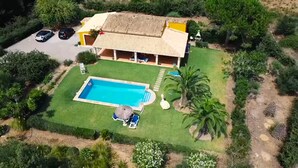 A house with a swimming pool, a covered patio, and a garden with palm trees. - VILLA  BOBIS - RUSTIC STAY (Pollensa)