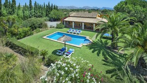 A pool with lounge chairs, a house with a tiled roof, and surrounding greenery. - VILLA  BOBIS - RUSTIC STAY (Pollensa)