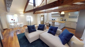A modern living room with a sectional sofa, a dining table, and a kitchen area.