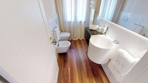 A bathroom with a bidet, toilet, and sink.