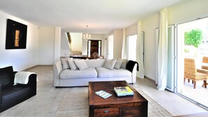 A modern living room with a light-colored sofa, a black armchair, and a wooden coffee table.