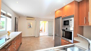 A modern kitchen with stainless steel appliances, wooden cabinets, and a large window.