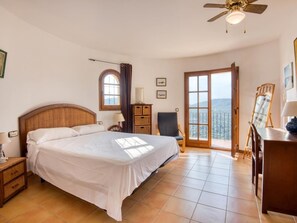 A bedroom with a large bed, a desk, a chair, a ceiling fan, and a view through a glass door. - Villa Torre Gavarres, Calonge - Costa Brava (Calonge)