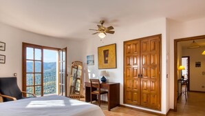 A bedroom with a bed, a desk, a chair, a mirror, a wardrobe, and a ceiling fan. - Villa Torre Gavarres, Calonge - Costa Brava (Calonge)