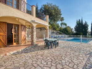 A stone patio with a pool, outdoor furniture, and a view of trees and a building. - Villa Torre Gavarres, Calonge - Costa Brava (Calonge)