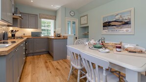 A modern kitchen with grey cabinets, a wooden countertop, and a dining area with white chairs.