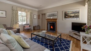 A living room with a fireplace, a sofa, a coffee table, and a television.