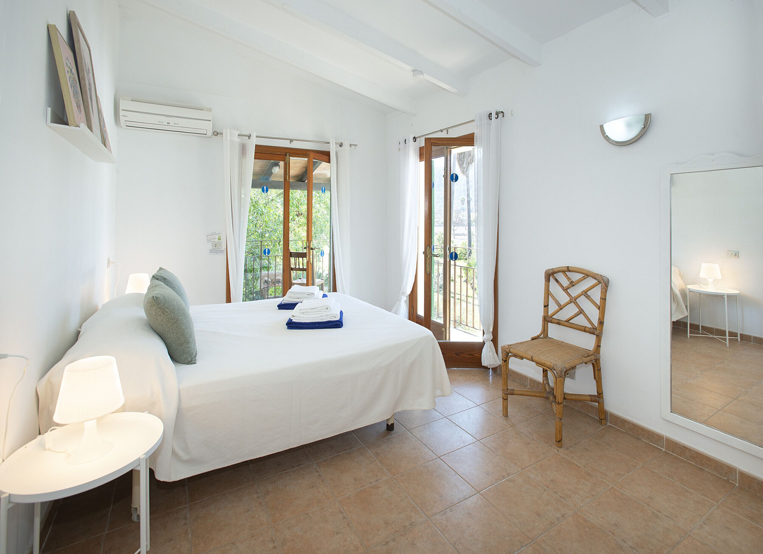 A bedroom with a bed, a chair, a table, and a window with curtains.