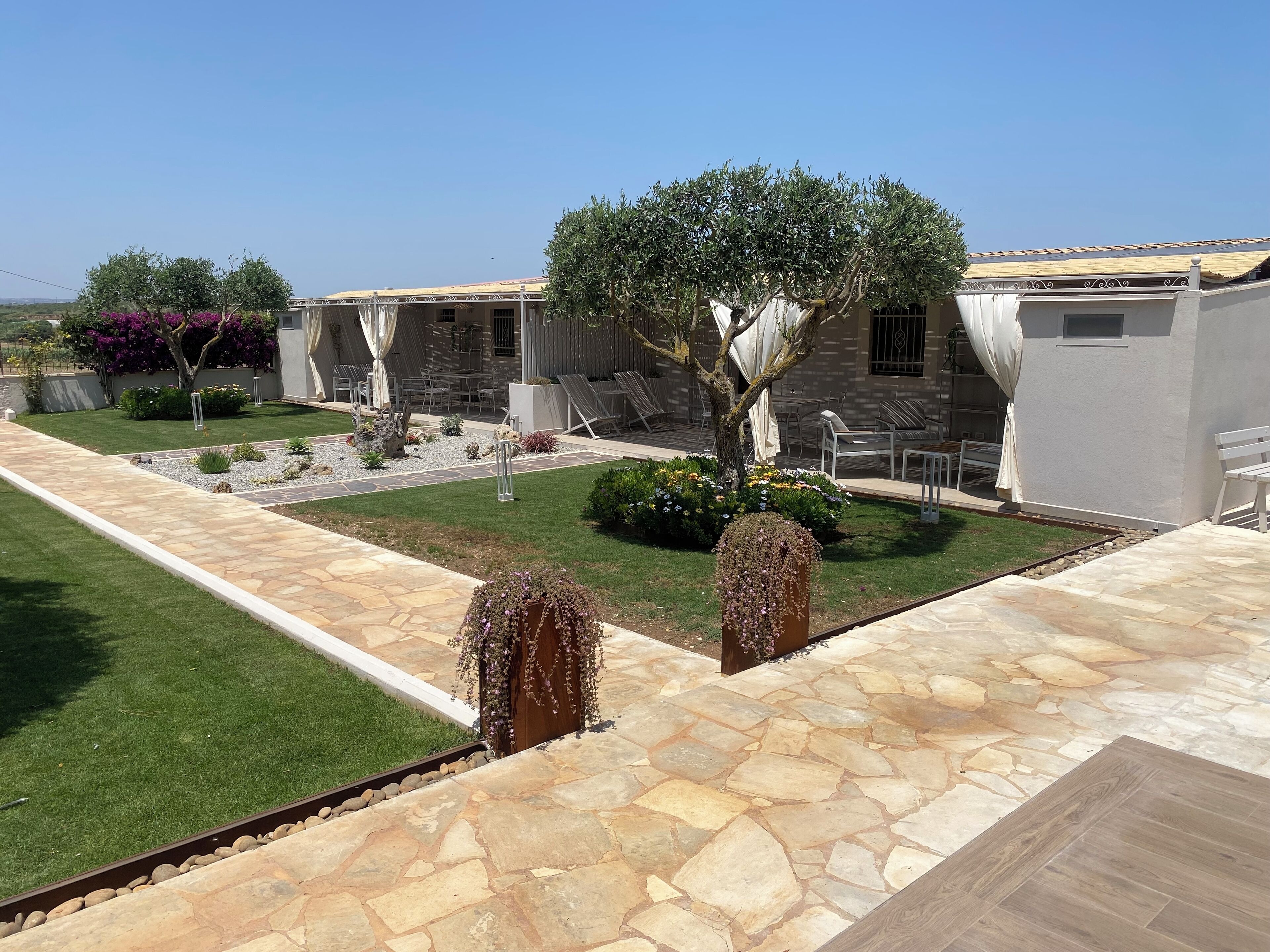 A courtyard with stone flooring, a lawn, and a building with outdoor seating.