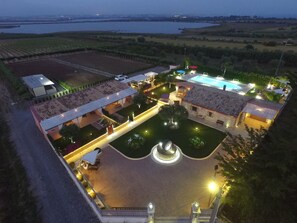 An aerial view of a resort with a swimming pool, a fountain, and a well-maintained lawn.