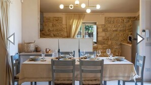 A dining area with a stone wall, a chandelier, and a view of the outside. - VILLA FENICOTTERO RELAX AND EXCLUSIVE POOL (Ispica)