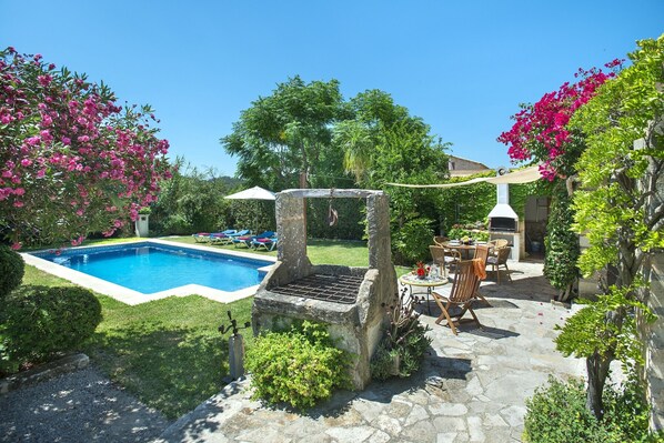 A backyard with a swimming pool, stone barbecue grill, and outdoor seating area. - VILLA EL CAMPET - RUSTIC STAY (Pollensa)