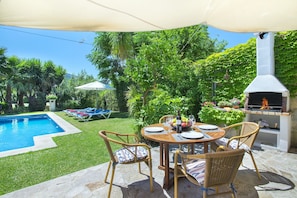 A backyard with a swimming pool, outdoor dining set, and a barbecue grill.