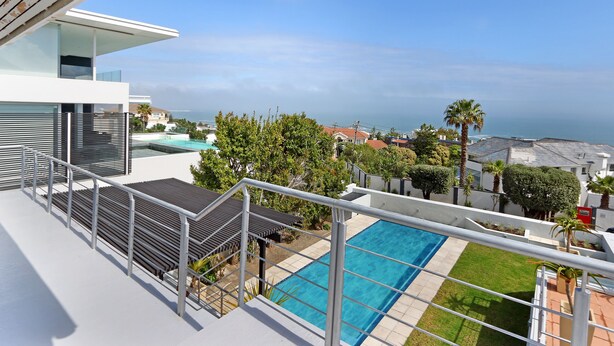Un bâtiment moderne doté d’une piscine sur le toit, offrant une vue dégagée sur l’océan et comprenant une pelouse bien entretenue.