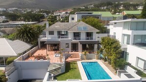 Une maison moderne à deux étages, dotée d’une piscine, d’un patio couvert et offrant une vue sur le quartier environnant.