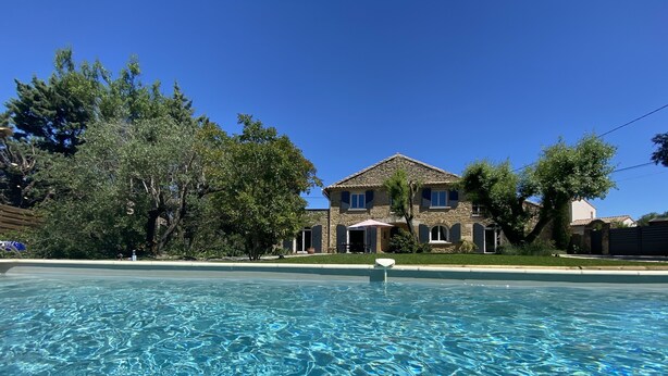 Una piscina nítida amb una casa de pedra al fons.
