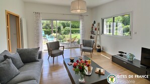 A modern living room with a sofa, chairs, a coffee table with flowers, a TV, and a bookshelf. - Ma Maison à La Mer, Fouesnant, Brittany (Fouesnant)