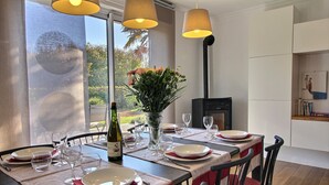 A dining area with a table set for four, a vase with flowers, and a fireplace. - Ma Maison à La Mer, Fouesnant, Brittany (Fouesnant)